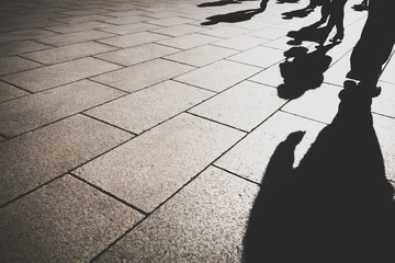shadow of people in day light on pattern granite city street, copy space on left