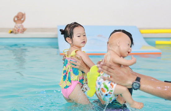 Little asian baby learning to swim.