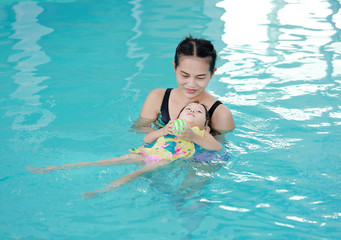 Mother with baby in swimming pool training.