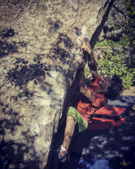 Naklejka premium Rock climber reaching for his next hand hold Joshua Tree National Park.