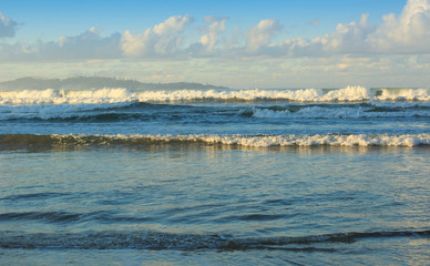 Wave running to the sand beach under blue sky