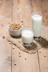 Soy milk or soya milk and soy beans in spoon on wooden table.