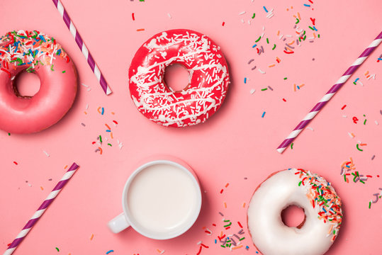 Donuts with icing and milk on pastel pink background. Sweet donuts.