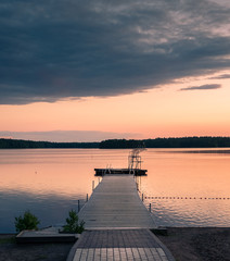 Naklejka na ściany i meble Landscape with pier and sunset at summer evening in the lake in Finland