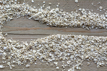 Many brown raw cereals in form of spoon are on the wooden background