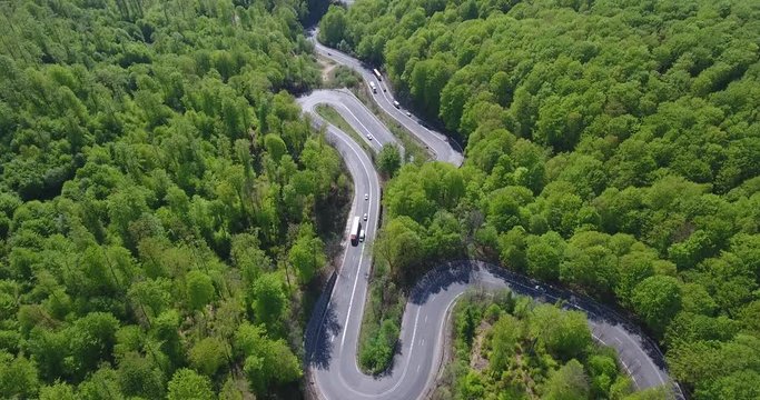 Winding road in the forest. Transylvania, Romania, Europe. Cars passing on road.