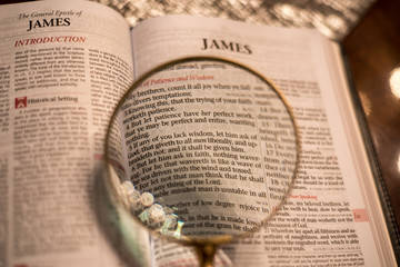 Reading with magnify glass the Bible James 1 - 150891342