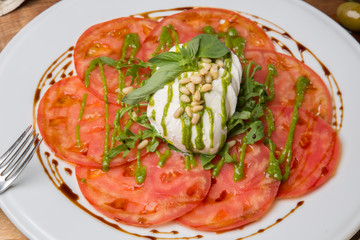 Serving Caprese salad on white plate in restaurant
