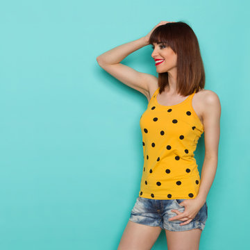 Smiling Young Woman In Yellow Dotted Tank Top Is Looking Away