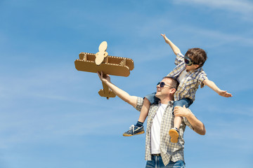 Father and son playing with cardboard toy airplane in the park at the day time.