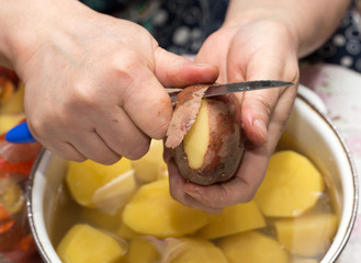 The cook cleans the potatoes with a knife