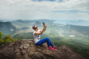 Naklejka na ściany i meble Women travel sit on a cliff on a rich forest mountain. Tab Kak Hang Nak Hill Nature Trail. Do selfie