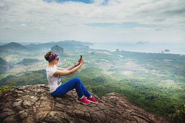 Fototapeta premium Women travel sit on a cliff on a rich forest mountain. Tab Kak Hang Nak Hill Nature Trail. Do selfie