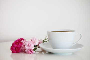 Cup of tea on white isolated background with flowers next to it