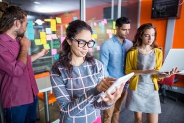 Smiling executives using digital tablet and laptop
