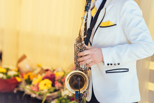 Saxophonist in white jacket plays the saxophone. Saxophonist jazz man with saxophone on wedding party