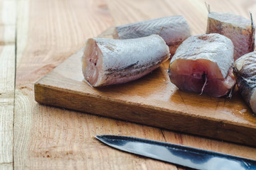Fototapeta na wymiar Chopped hake fish and a knife on a wooden board