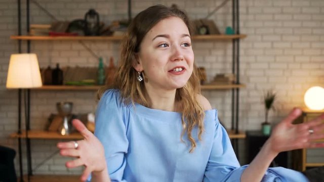 portrait young exited woman speaks emotionally and blab actively without stopping to the camera with actively gestures