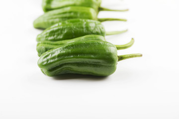 Close-up of green peppers placed in line on white background. Healthy food.