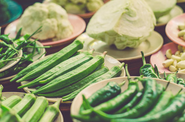 Various vegetables display on wooden table for sale at fresh market stall with faded color effect.