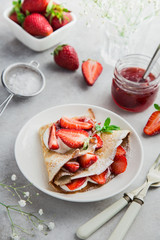 crepe served with cream cheese and fresh strawberry on white plate
