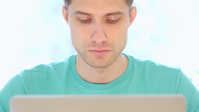 Young Man Working On Laptop in Office, Front View Close Up