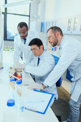 Professional scientists in white coats working together in chemical laboratory