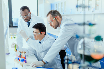 Professional scientists in white coats working together in chemical laboratory - obrazy, fototapety, plakaty