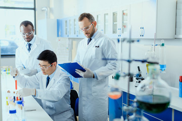Professional scientists in white coats working together in chemical laboratory