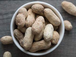 Peanuts in shells in a white bowl