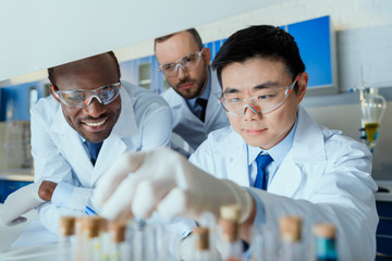 Multiethnic group of scientists in protective eyeglasses working together in chemical laboratory
