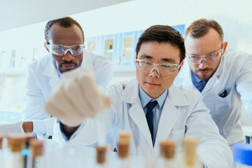 Multiethnic group of scientists in protective eyeglasses working together in chemical laboratory
