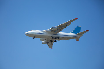 Fototapeta na wymiar A white airplane flying in a clear pale blue sky.