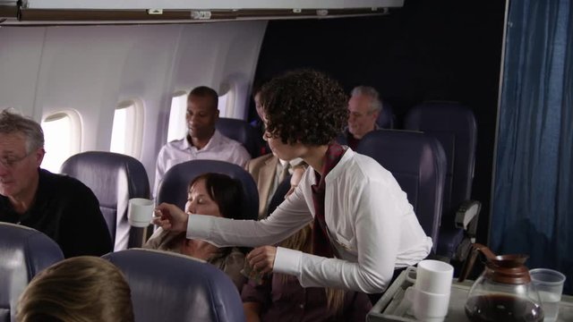 Flight attendant serving drinks to airliner passengers