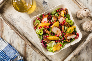 Spring salad with chicken, pomegranate, orange, pecan nuts and honey.