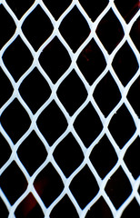 Fototapeta premium White plastic mesh agains black backdrop