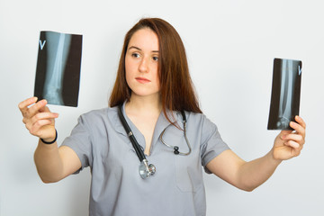 Young female doctor with stethoscope looking at the x-ray picture on white background