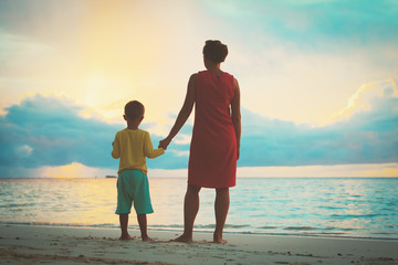 mother and son walking on sunset beach