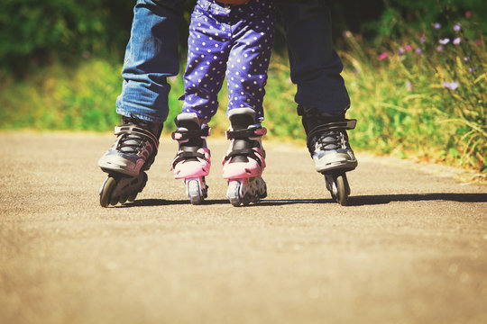 father teaching little daugther to roller skate