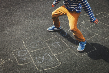 little boy playing hopscotch on playground