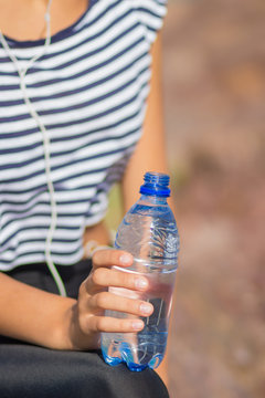 A bottle of water close-up. The girl drinks water during fitness outdoors