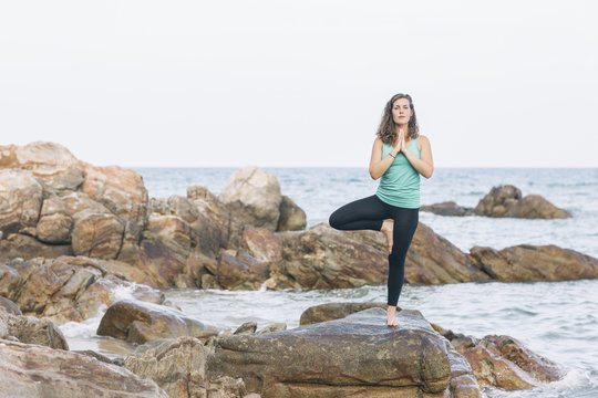 Woman practicing yoga on a rock at the sea