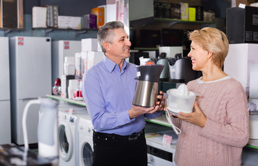Husband and wife in shop of household appliances choose juicer