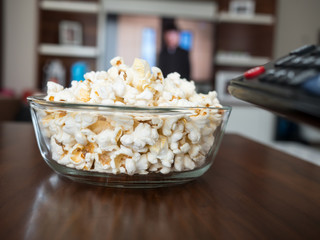 Popcorn in a bowl with a remote on  tv background
