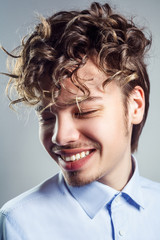 Fototapeta premium Portrait of young man with curly hairstyle. studio shot. toothy smile and closed eyes.