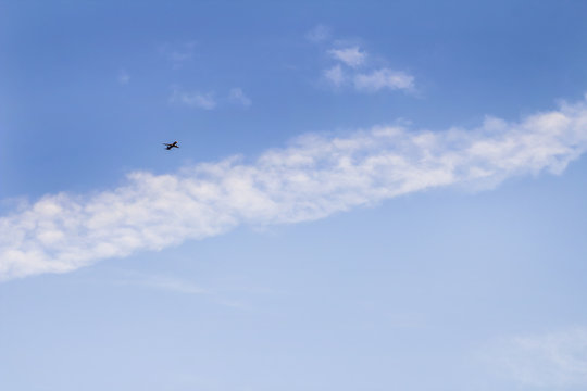 The plane flies through the blue sky
