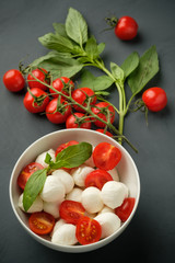 Mozzarella cheese, basil and tomatoes cherry on a gray background