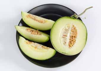 
Cantaloupe melon slices sitting on black plate 
