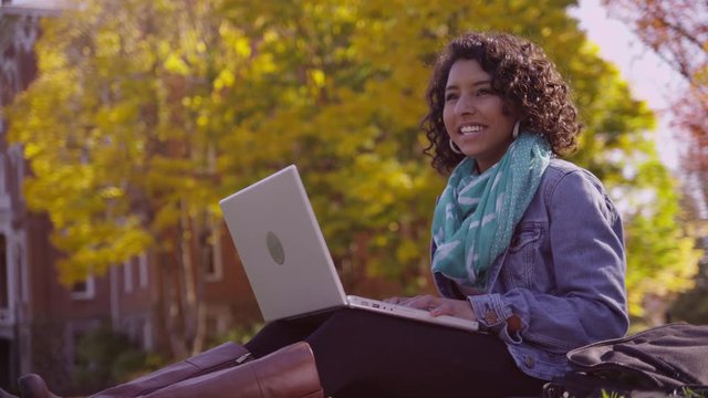 College student on campus in fall using laptop computer