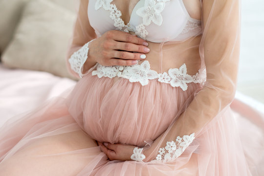Image of pregnant woman touching her belly with hands. Closeup